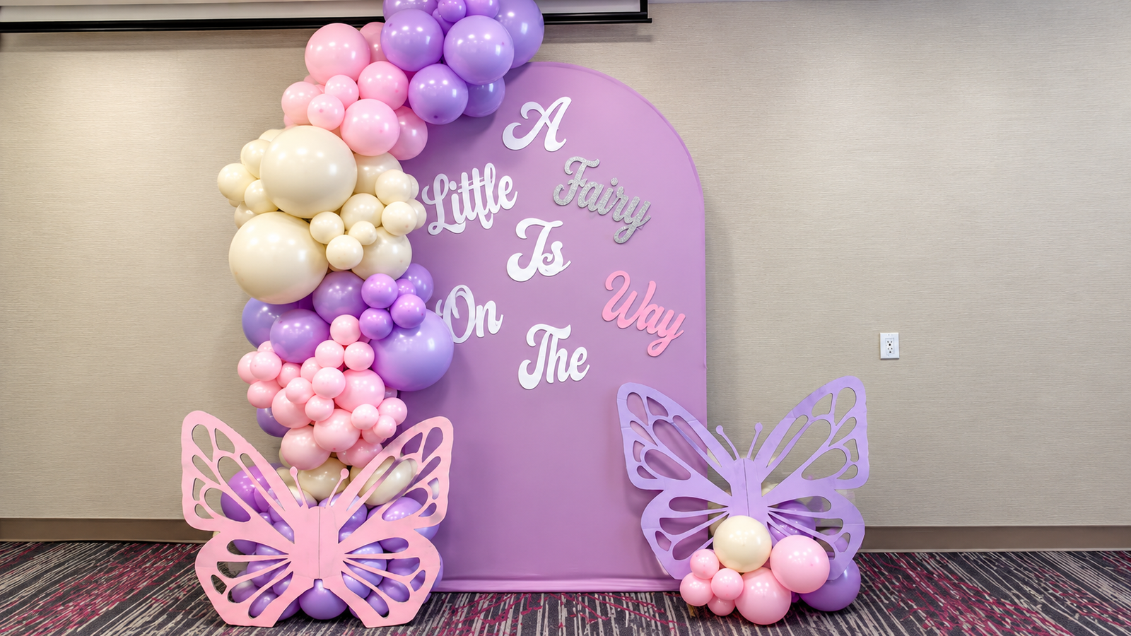 Pink, lavender and cream organic garland beside a fairy themed arched backdrop with butterfly cutouts